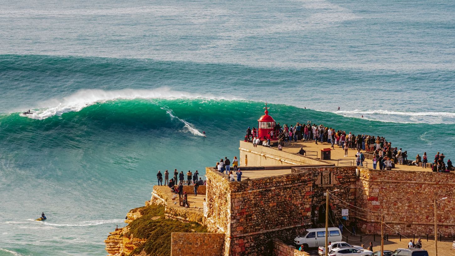 marciano riding giant wave in front of nazare cliff